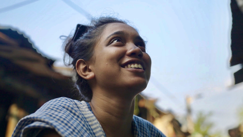 Jaunas sievietes tuvplāns, viņa smaida un skatās augšup.