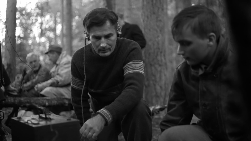 Vīrieši mežā nospriegotā un noslēpumainā atmosfērā koncentrējas uz radioiekārtu.