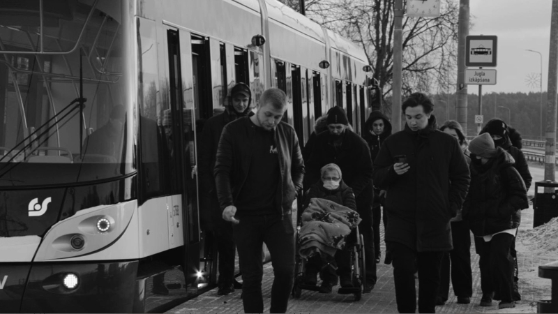 Melnbaltā attēlā redzams, kā no Rīgas Satiksmes tramvaja izkāpj pasažieri.
