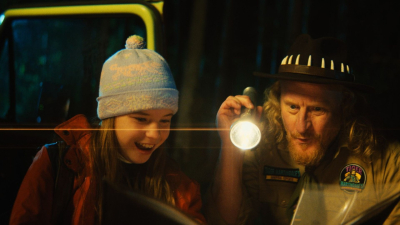 Meitene un vīrietis tumsā kopā skatās kartē, vīrietis tur rokā ieslēgtu lukturīti.